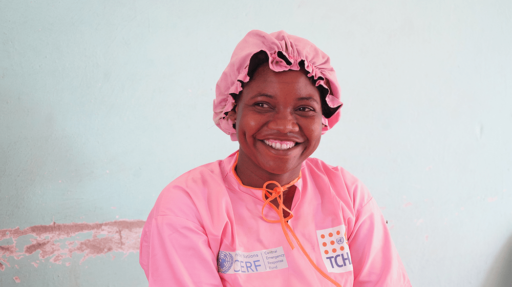 Una mujer sonríe vestida con ropa médica rosada