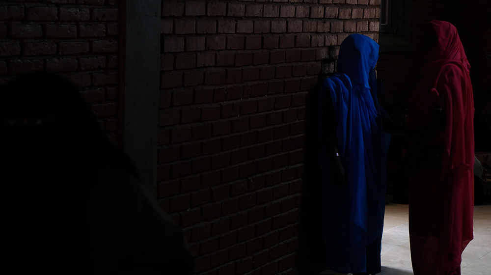 Two women stand in a dark street.