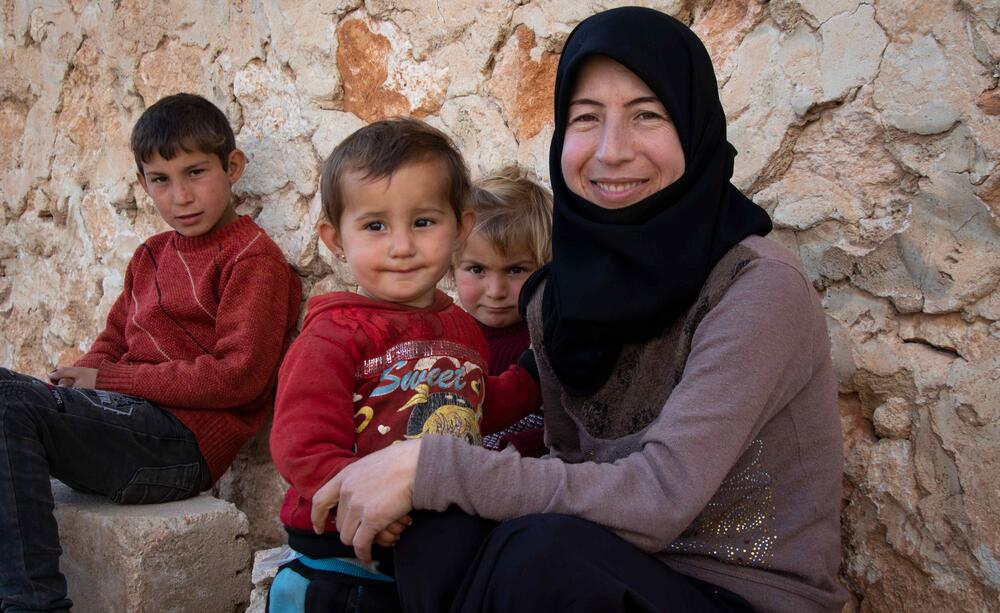 أم وأطفالها الثلاثة يبتسمون لالتقاط صورة عائلية.