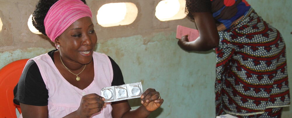 A woman holds a packet of condoms. 