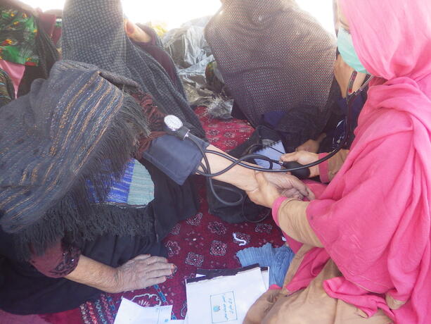 A midwife measuring the blood pressure of an older woman. 