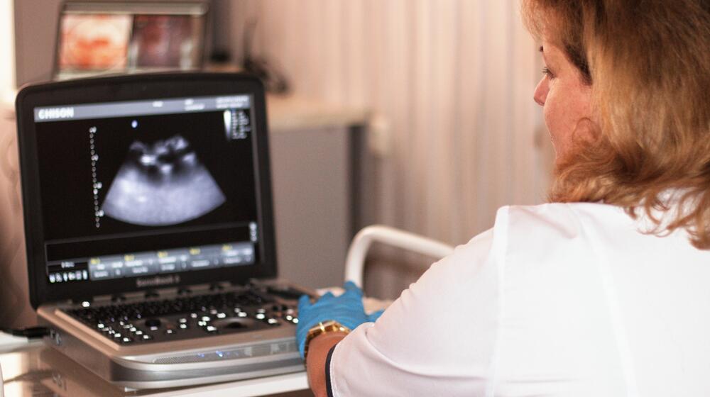 A doctor uses medical technology to scan a pregnant woman.