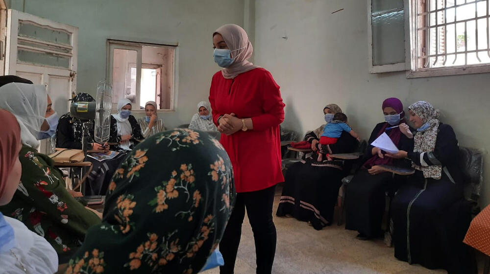 A staff member holds a training session with a group of women.