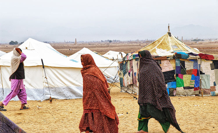 Women in full veils covering their faces walk near tents.