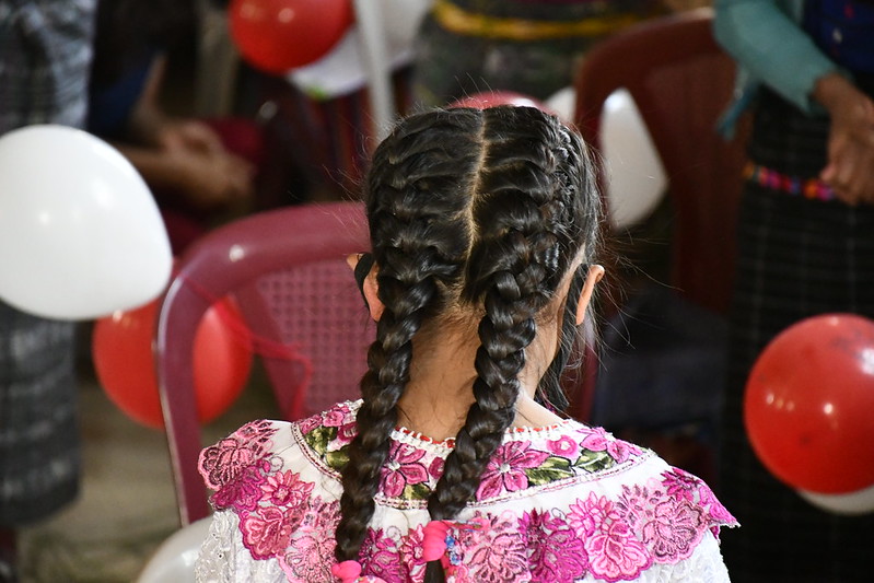 Una niña con trenzas y globos vista desde atrás.