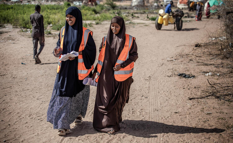 Two community health volunteers walk in a drought-affected area. 