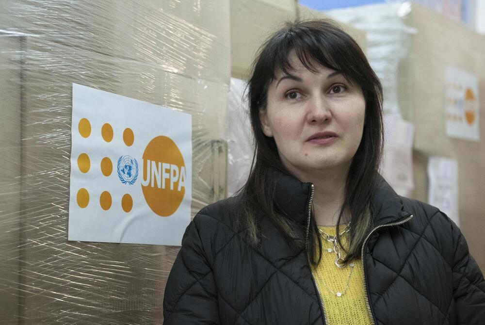 A woman stands in front of UNFPA equipment. 