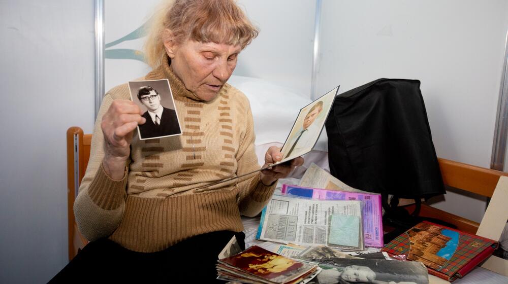 An elderly woman shows photographs.