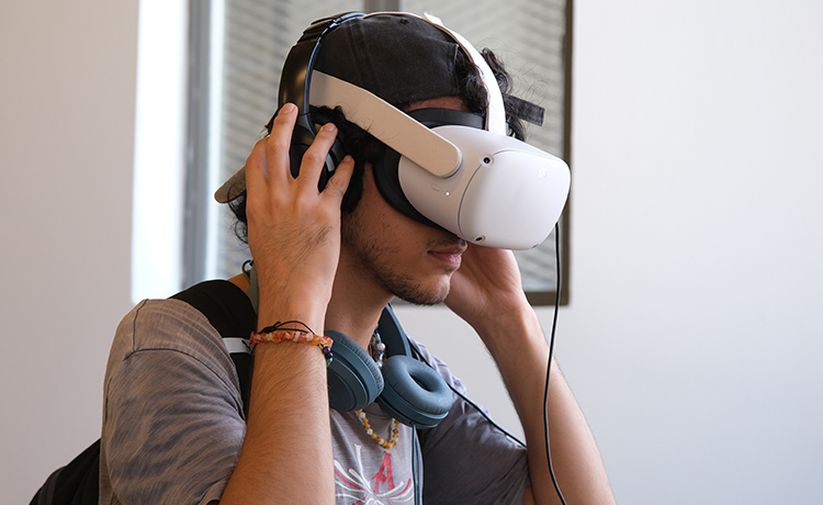 A young man wears a virtual reality headset.