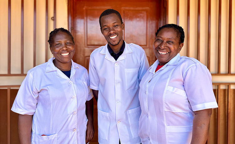 Three health workers stand outside together.