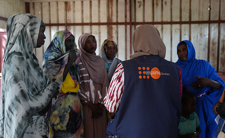 A group of women talk, one of them is wearing an UNFPA jacket.