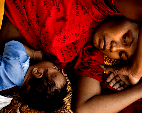A mother lies next to her newborn baby.