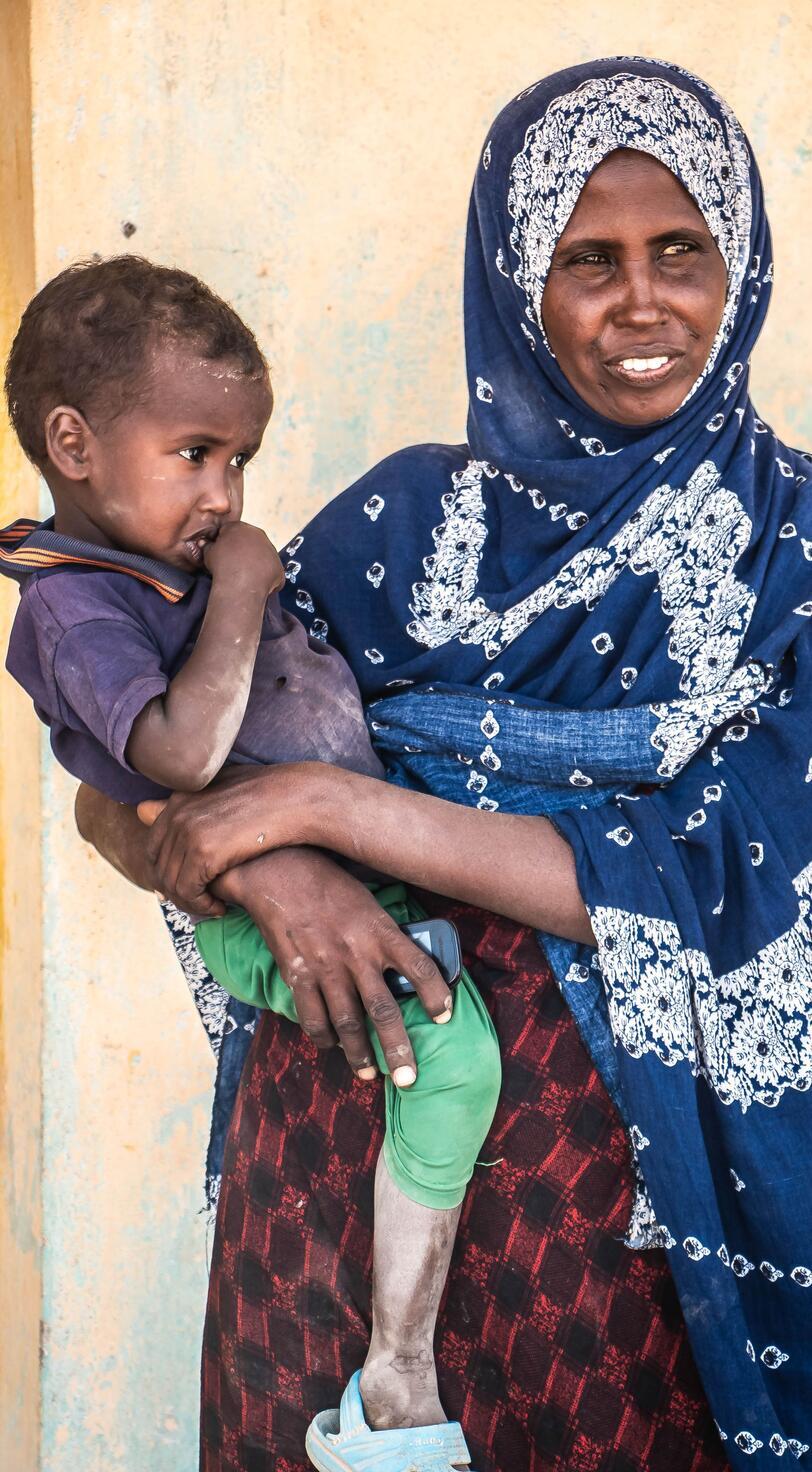 A woman carries a small child.