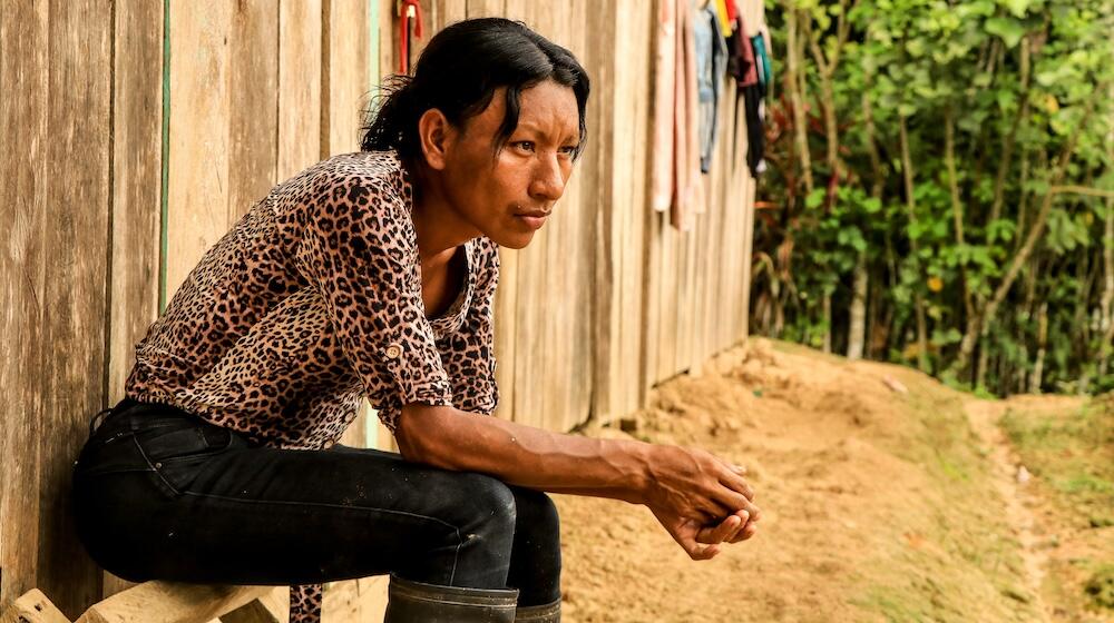 A trans woman who lives and works in the Amazonian area of Peru, sits outside of a building.