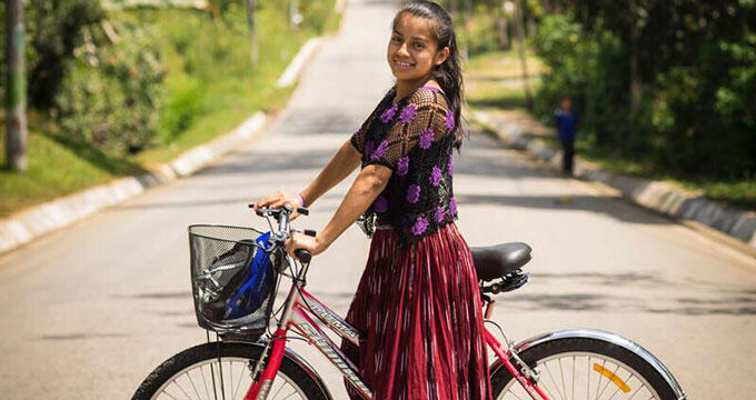 Girl stands with bike smiles at camera