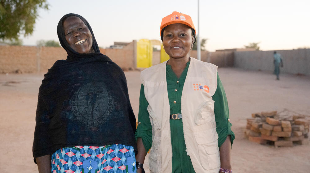 Two women who work at a social centre to promote gender equality and raise awareness of GBV look towards the camera and smile. 