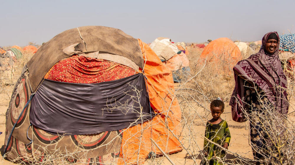 A family stands beside a tent in the desert.