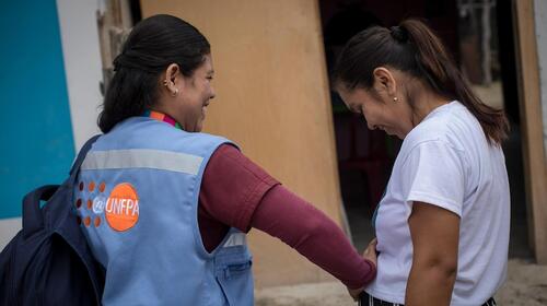 A UNFPA midwife nurturingly places her hand on a pregnant woman. 