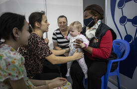 Ukrainian Mother hands her baby to Dr Natalia Kanem to hold. Surrounded by two other women