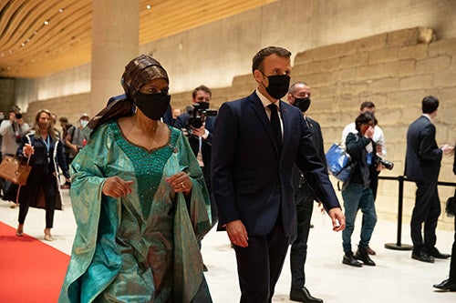 Phumzile Mlambo-Ngcuka and Emmanuel Macron walk into a convention hall. They are wearing face masks.