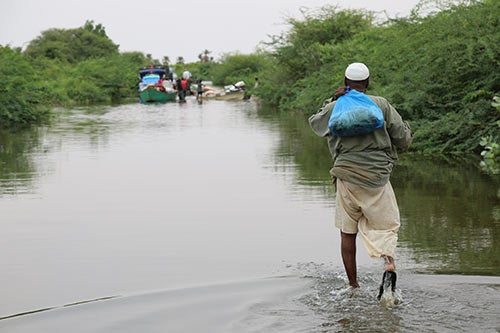 A man carries his belongings in a plastic bag as he wades through floodwater. 