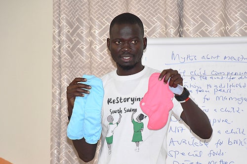 Data Gordon holds up reusable menstrual pads as he speaks to a group of men about menstruation myths.