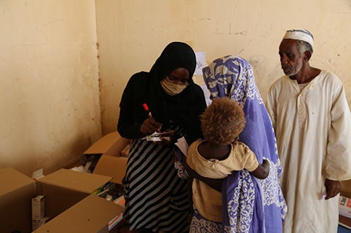 A woman takes information from a family affected by floods.