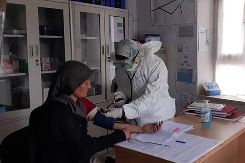 A midwife in full protective gear tends to a woman at a family health house. 