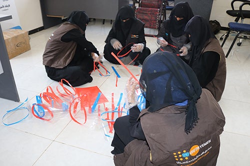 Women in a safe space assemble face shields.