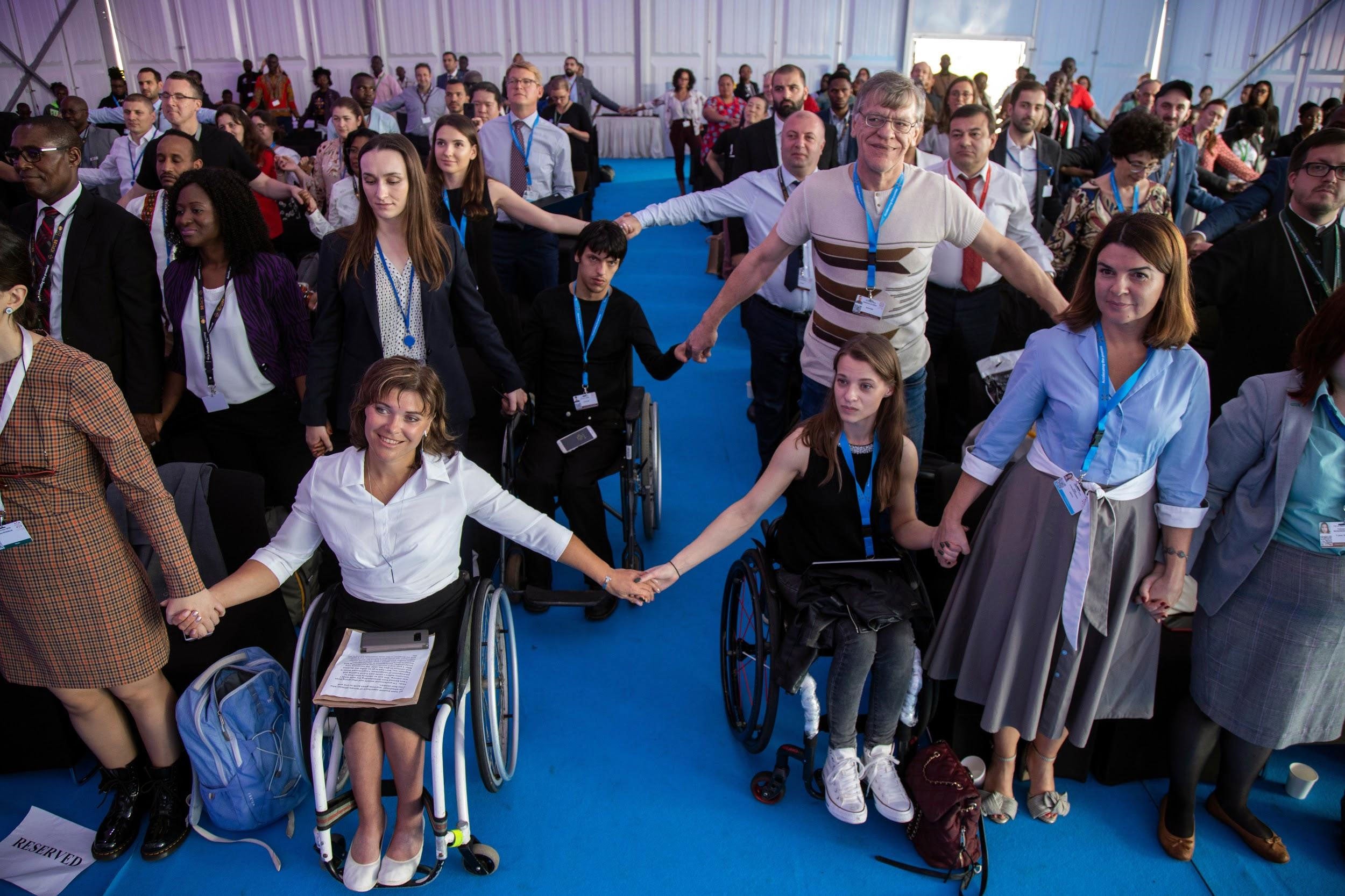 Individuals in attendance for the Nairobi Summit on ICPD25 hold hands.