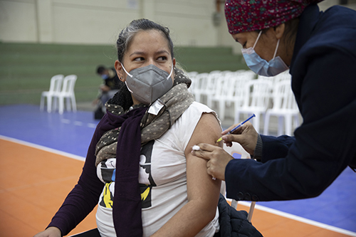 A pregnant woman in a face mask receives a COVID-19 vaccination. 