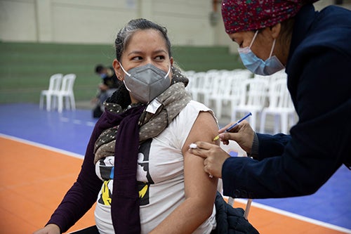 A pregnant woman in a face mask receives a COVID-19 vaccination. 