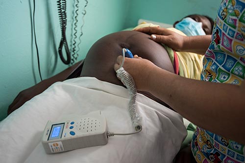 Lucia has a prenatal check up, with a health worker using a device to listen for a fetal heartbeat. 