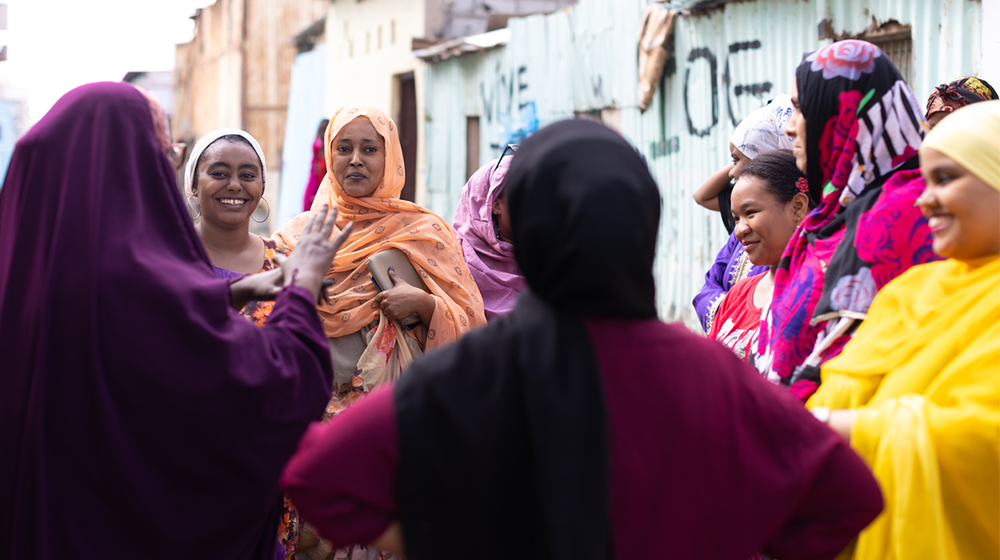 A group of women smiling and speaking together outside
