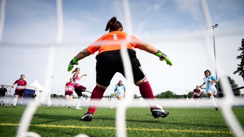 A goalkeeper defends a goal during a game of women's soccer.