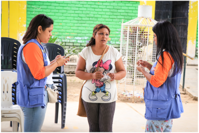 Trois femmes se tiennent debout. Deux d’entre elles sont des prestataires de santé et portent des vêtements indiquant « UNFPA ».