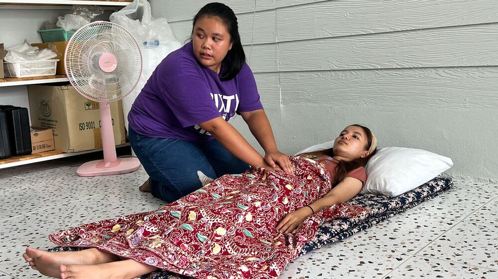 Una mujer realiza un masaje abdominal a una joven, que está tumbada.