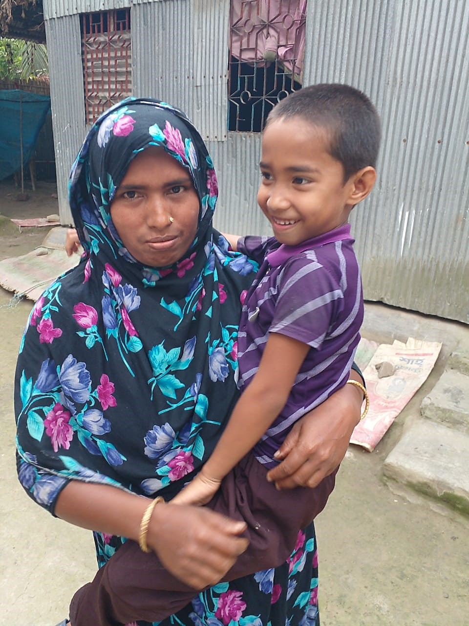 A young child smiles as he is held by his mother.