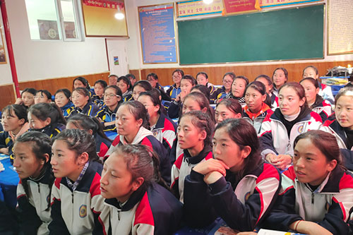 Girls in a classroom pay close attention to their instructor.