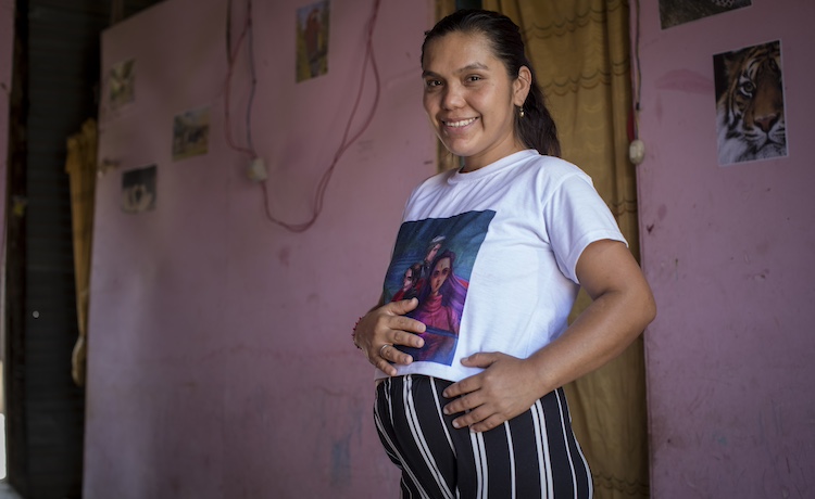 A pregnant woman smiles.