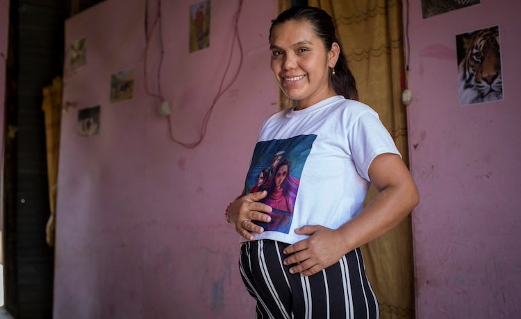 A pregnant woman smiles.