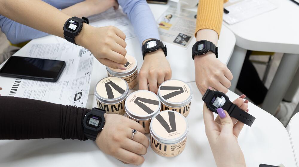 A group of people in Moldova pose with IMMI watches around their wrists.