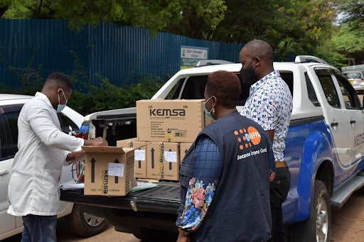 Supply packages in the back of a white pick-up truck are received by staff.  