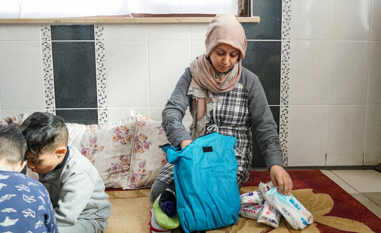 A woman opens a bag of supplies. 
