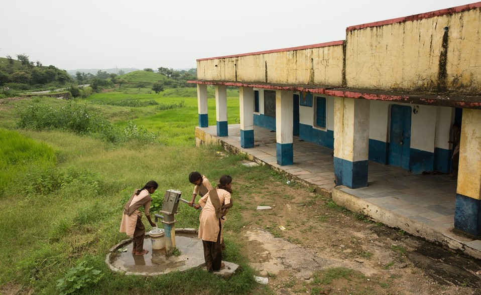 A group of girls pump water from a well.
