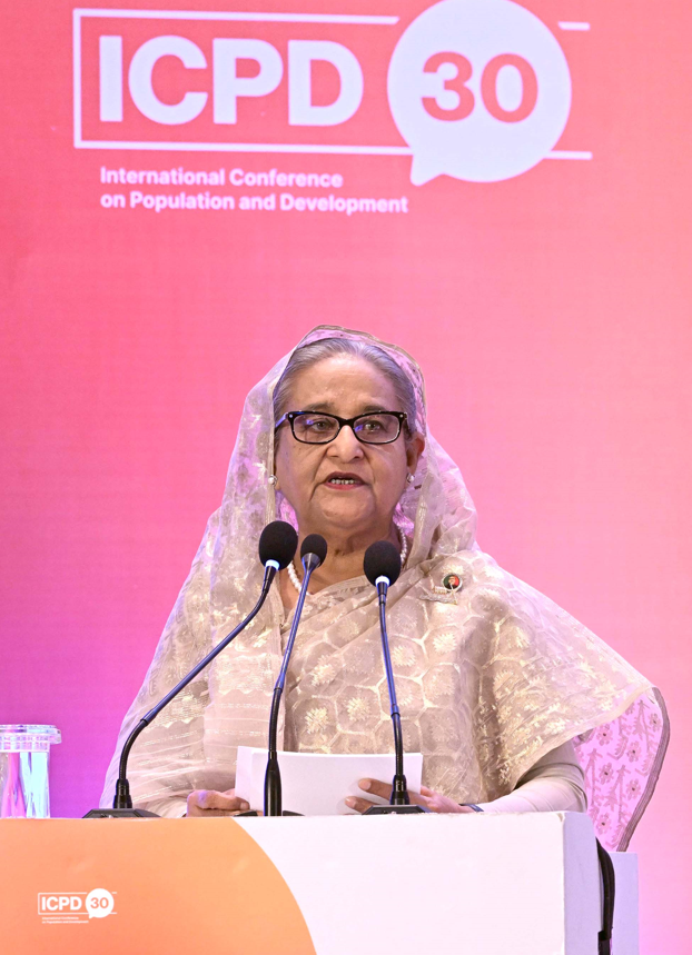 The Prime Minister of Bangladesh stands at a podium speaking. 