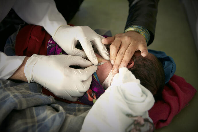 A midwife providing a health service to a newborn child. 