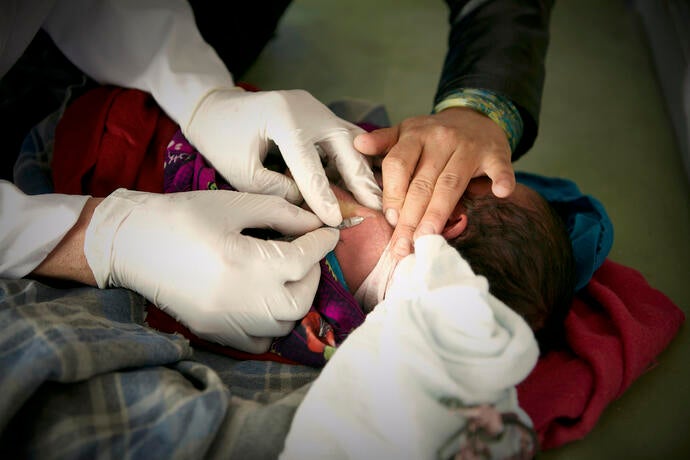 A midwife providing a health service to a newborn child.