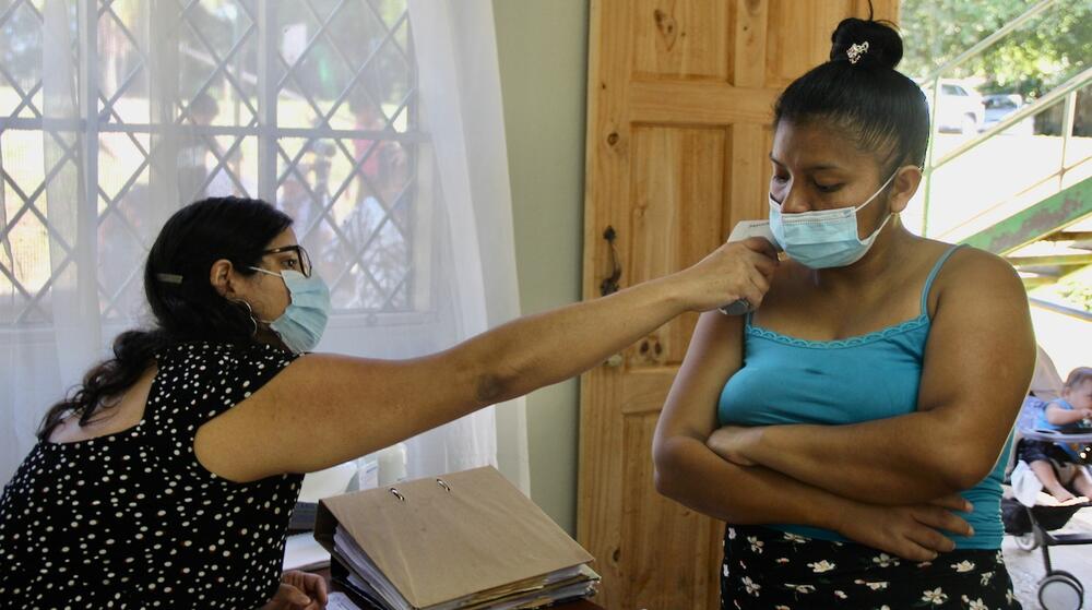 A health worker helps a female patient.