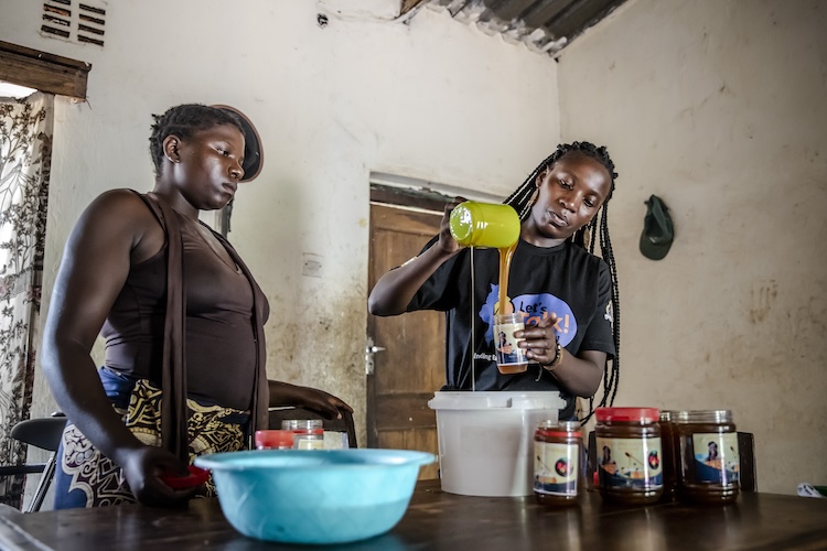 Two young women in Malawi filling jars.